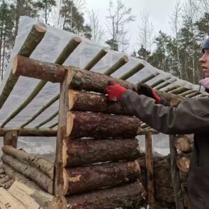 Winter bushcraft survival shelter built in a snowy forest with logs and insulated walls