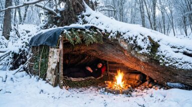 Solo winter bushcraft shelter built in deep snow for overnight survival
