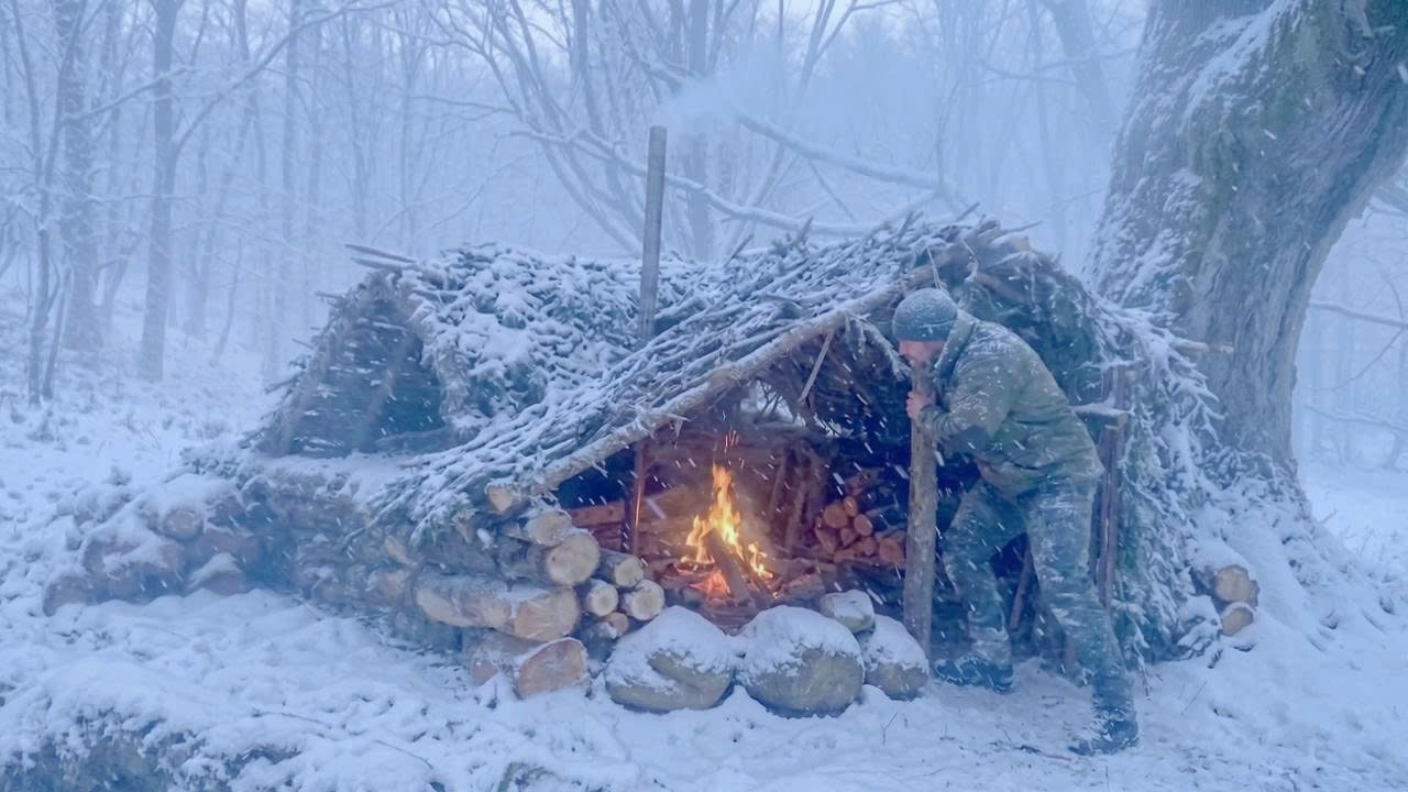 Building a wilderness survival shelter from branches during a snowstorm