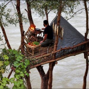 Elevated river treehouse bushcraft shelter built from natural wood above a rushing river