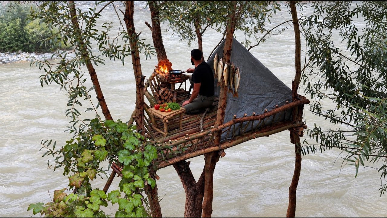 Elevated river treehouse bushcraft shelter built from natural wood above a rushing river